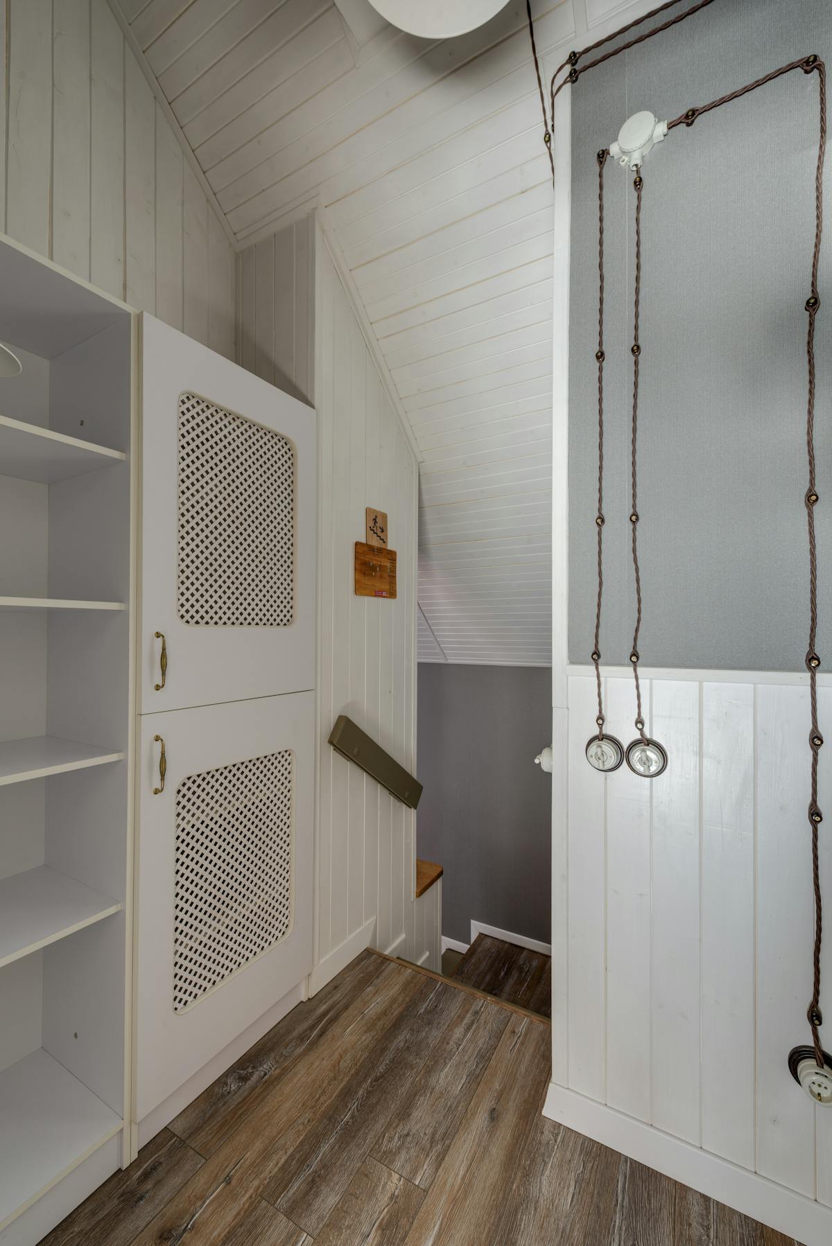 Real fitted cupboards with lattice fretwork door inserts, sat against tongue-and-groove wall panelling — used as fretwork inspiration.